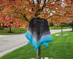 a tree that has been decorated with blue and black yarn on it in the grass