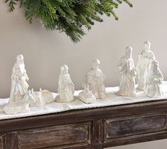 a group of white figurines sitting on top of a wooden table next to a christmas tree