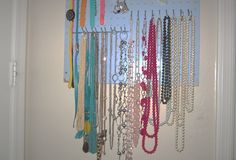 a bunch of necklaces are hanging on the wall in front of a white door