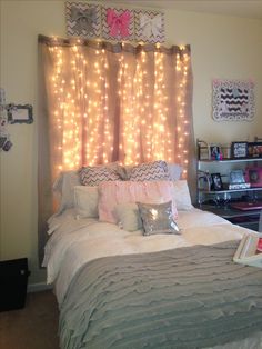 a bed room with a neatly made bed and some lights on the wall above it