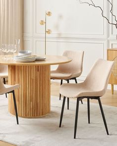 a round table with four chairs around it in a living room next to a white rug