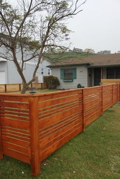 a wooden fence in front of a house with a tree growing on top of it