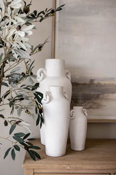 two white vases sitting on top of a wooden table