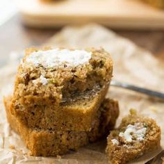 two muffins sitting on top of a piece of wax paper next to a knife