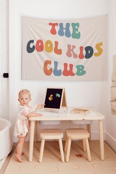 a baby sitting at a table in front of a wall with a sign on it that says long live playtime