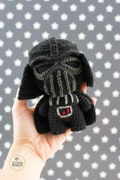 a hand is holding a small knitted darth vader toy in it's palm