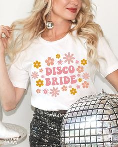 a woman in a white t - shirt is holding a disco ball and posing for the camera