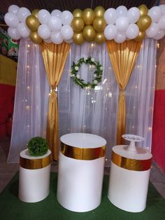 balloons and decorations are on display in front of a curtained backdrop with gold trim