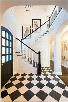 an entryway with black and white checkered flooring, framed owls on the staircase