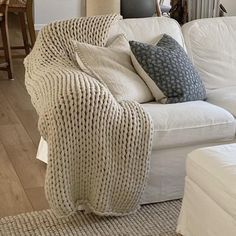 a living room filled with white furniture and lots of pillows