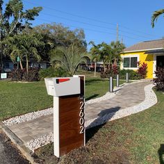 a mailbox sitting on the side of a road in front of a yellow house