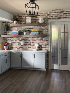 a kitchen with white cabinets and brick walls