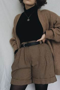 a woman in black shirt and brown shorts posing for the camera with her hands on her hips