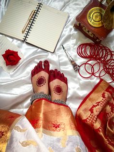 a person's feet with hennap on top of a bed next to an open notebook