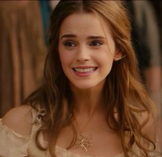 a woman with long hair smiling and wearing a white dress in the movie beauty and the beast