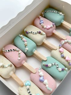 there are many different colored ice creams on the stick in the box with pearls