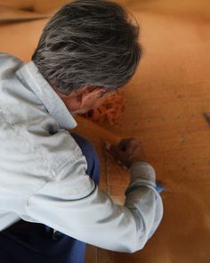 an older man is working on a piece of art with scissors and paper in his hands