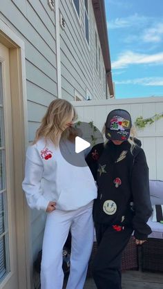 two people in costumes standing on the outside of a house with their faces painted black and white