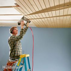 a man is painting the ceiling in his room with headphones and a paint roller