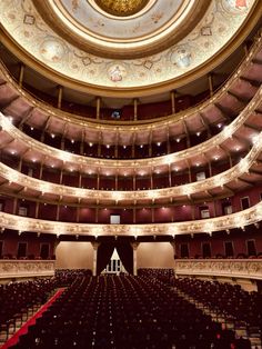 an empty auditorium filled with lots of seats and a ceiling painted in gold, red and white