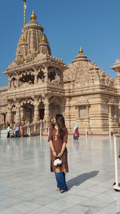 a woman standing in front of a building with gold domes on it's sides