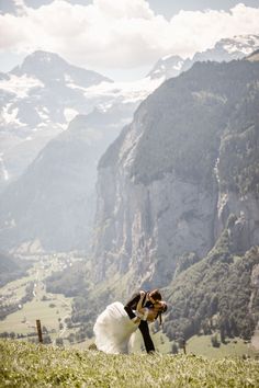 a bride and groom kissing in the mountains