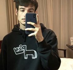 a young man taking a selfie with his cell phone in front of him and wearing a black hoodie