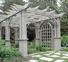 an outdoor garden with stone walkways and pergolated arbor, surrounded by greenery