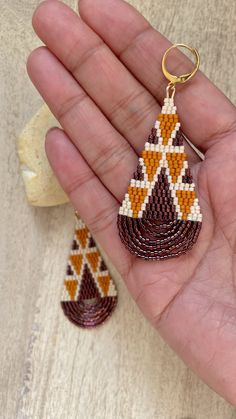 a hand holding a pair of beaded earrings