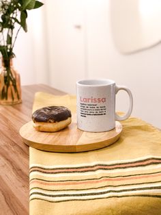 a donut sitting on top of a wooden table next to a cup