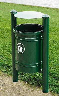 a green trash can sitting on top of a grass covered field