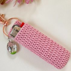 a pink crocheted case with a keychain hanging from it's side