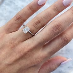 a woman's hand with a diamond ring on top of her finger and the other hand holding it