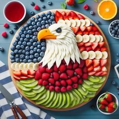 an eagle made out of fruit on a platter with berries, kiwis and strawberries