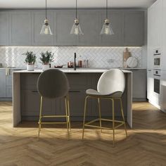 two green chairs sitting in front of a kitchen island