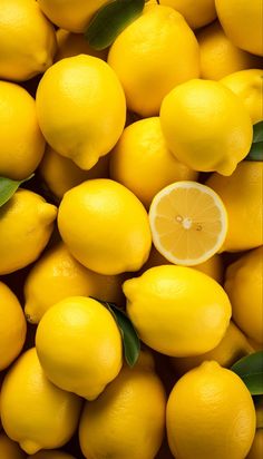 a pile of yellow lemons with green leaves