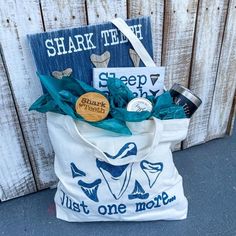 a tote bag with shark toothbrushes and other items in it sitting next to a wooden fence