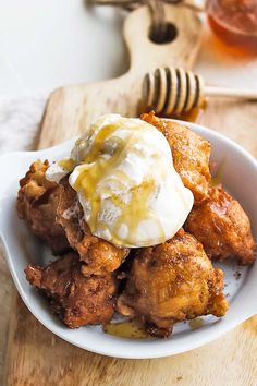 a white bowl filled with fried food on top of a wooden cutting board next to a honey comb