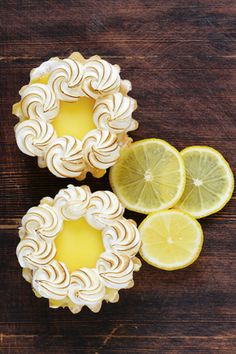 two lemon pies with one cut in half and the other whole on a wooden table