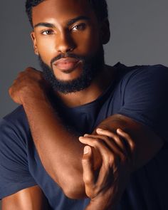 a close up of a person wearing a blue shirt and holding his arms crossed in front of him