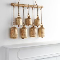 four bells hanging on a wall next to a fireplace