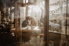 two people sitting at a table in front of a window with the sun shining through