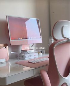 a desk with a computer monitor, keyboard and mouse on it in front of a pink chair