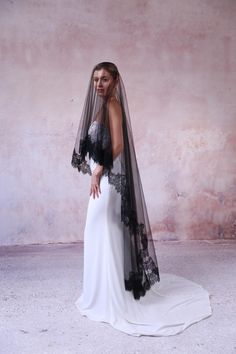 a woman in a wedding dress with a black veil on her head is posing for the camera