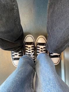 two people standing next to each other wearing sneakers