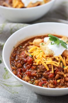 two white bowls filled with chili and cheese