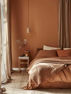 a bedroom with an orange wall and brown bedding in the corner, there is a small table next to the bed