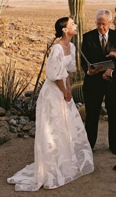 a man and woman standing next to each other in front of a cacti