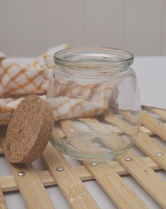 a glass jar sitting on top of a wooden table next to a corked object