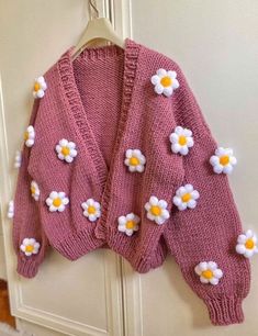 a pink sweater with white and yellow flowers on it